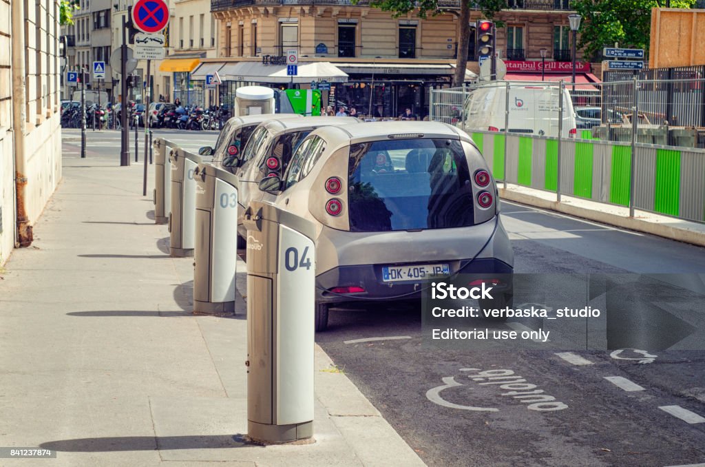 Charging car station Autolib in Rue Henri Barbusse Paris,  France - June 5, 2017: Back view of sharing car station Autolib is located at 66 Rue Henri Barbusse. Three metallic color electric autos are charging here. In the foreground there is recharging unit number 4 with empty parking space. Boulevard de Port-Royal and unidentified pedestrians are visible in the background. Sunny summer day. Paris - France Stock Photo
