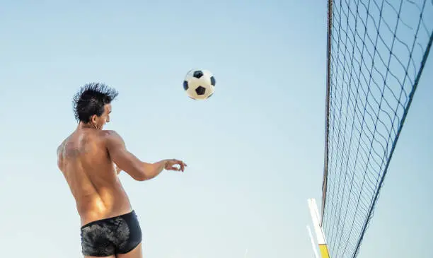 brazilian man heading soccerball over volleyball net at beach in Rio de Janeiro