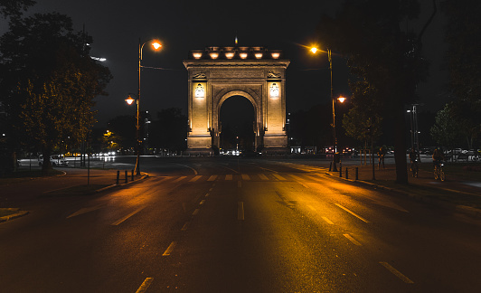 The Arcul de Triumf (Arch of Triumph) in Bucharest, lit up by lights during the night.
