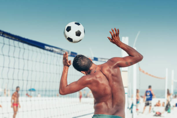 hombre brasileño título balón de fútbol sobre la red del voleibol en la playa - brazil beach copacabana beach recreational pursuit fotografías e imágenes de stock