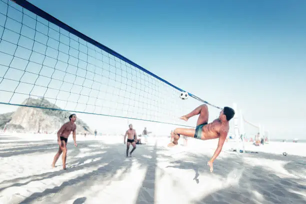 brazilian man kicking soccerball over volleyball net at beach in Rio de Janeiro