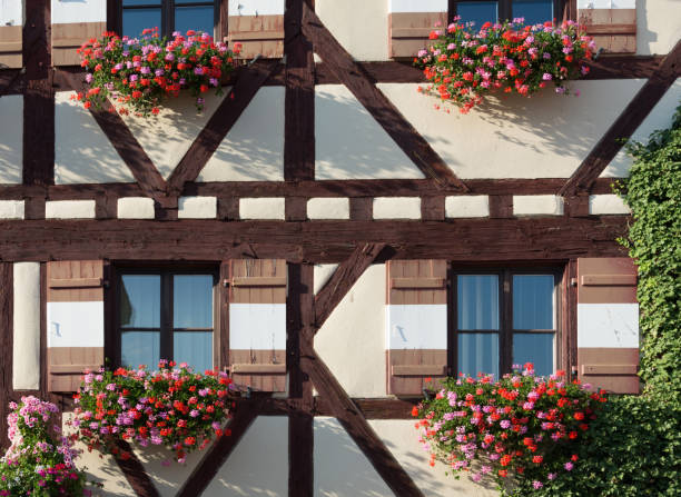 Half-timbered house with several window shutters and colorful flowers