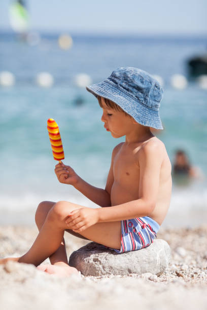 dulce poco hijo, niño, comer helado en la playa - ice cream licking little boys ice cream cone fotografías e imágenes de stock