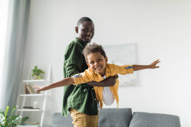 istock afro father and son playing at home, pretending airplane 841264888