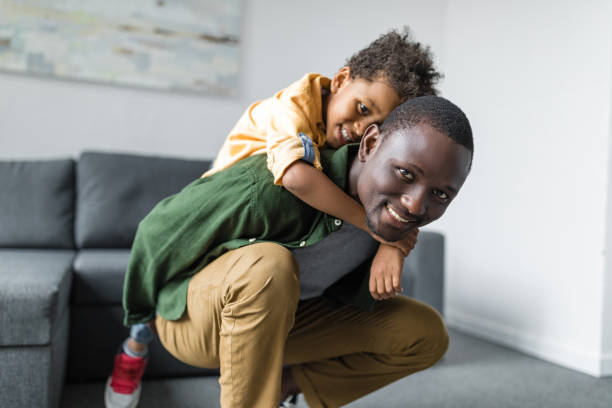 istock cute little afro son piggybacking on father at home 841269054