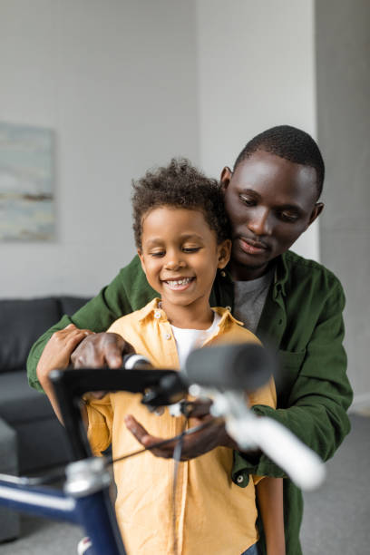 istock happy smiling father and son playing with bicycle at home 841275904