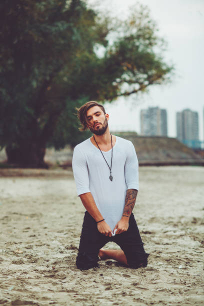 istock Handsome man kneeling on the sand by the river 841279090
