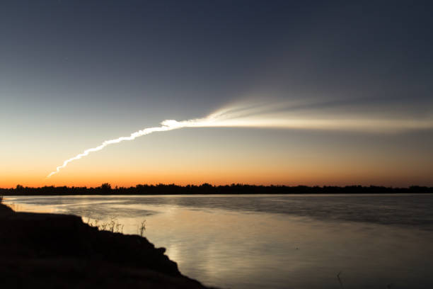istock Smoke trail from a rocket at sunset with reflection in water 841281724