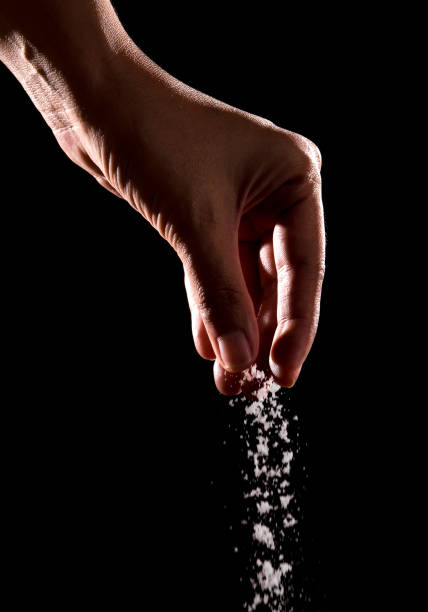 istock Hand sprinkling salt,salt over black background. 841282036