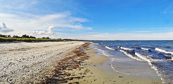Beach in Marielyst, denmark with ocean waves of baltic sea and blue sky - panorama view