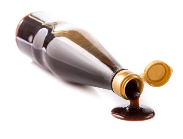 Oyster sauce poured from a bottle on a white background