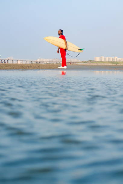 istock Man holding a surfboard on the beach 841303930