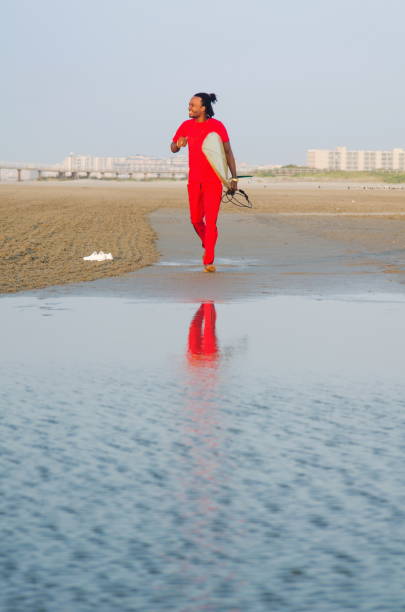 Man running with a surfboard on the beach