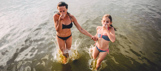 mãe e filha pulando na água - river swimming women water - fotografias e filmes do acervo