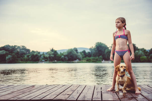 istock Little girl and her dog standing on a dock 841311622