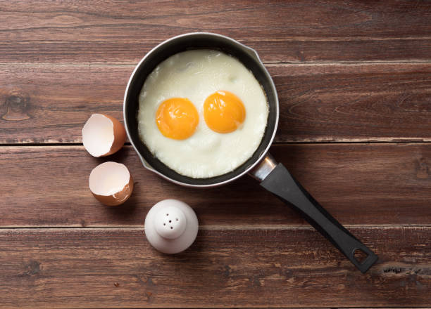 istock Fried eggs in a frying pan on wooden table, top view 841314346