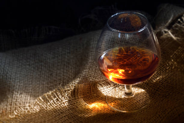 istock Cognac or brandy in a glass with a glowing light reflex on rustic burlap, concept for enjoyment or addiction, copy space 841345030