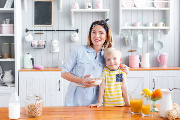 мать и сын улыбаются во время завтрака на кухне. смотреть в камеру - smart casual occupation casual healthy eating стоковые фото и изображения