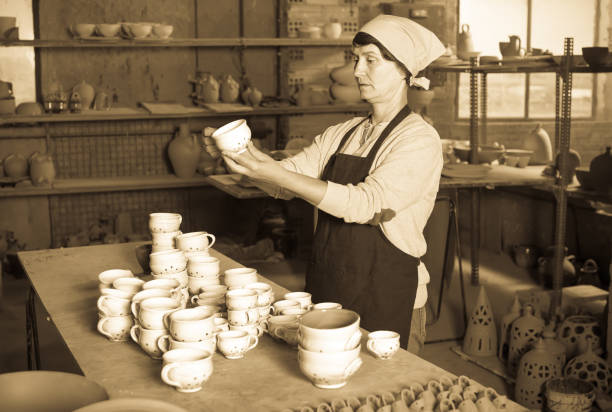 Portrait of an elderly woman displaying cups at the workshop