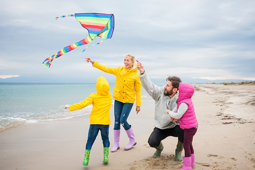 Young Family Flying Kite On Beach