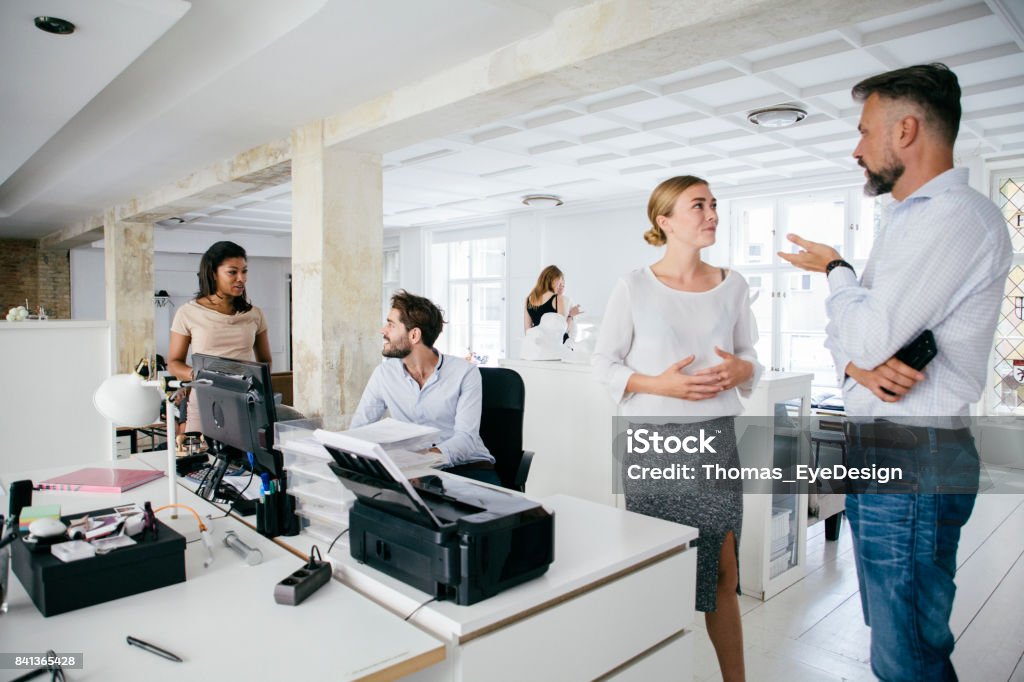 Young Professionals Working Together In Modern Office Space A group of young professionals working together in a bright, modern office space. Bright Stock Photo