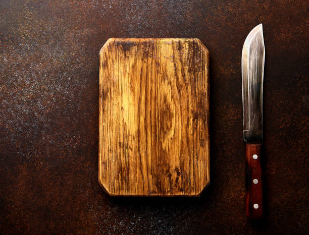 istock Knife for meat and wooden board on brown concrete table. Top view. 841368486