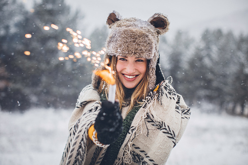 Cute woman on snowy day with sparkler