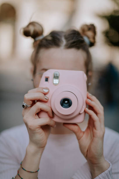 в любви с розовым цветом и этой мгновенной камерой - photographer women retro revival camera стоковые фото и изображения
