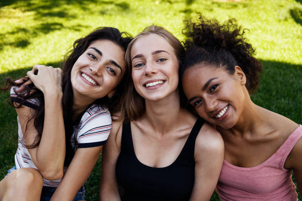 istock Happy female friends sitting in park on a grass 841380584