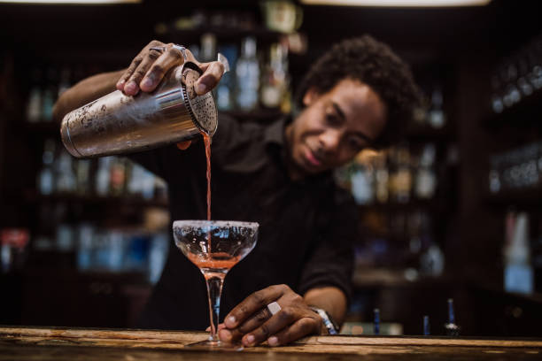 joven bartender vierte cócteles en un bar de copas - cocktail alcohol drink black fotografías e imágenes de stock