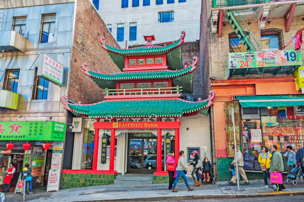 San Francisco, California, USA - February 18, 2017: This people walking by the Chinese Style bank building in the heart of San Franciscos Chinatown has architectural features expected in a tourist oriented Chinese Community. This building has history going back to the Gold Rush era of California these many visitors of this area the men and women take this view as expected in this community but it is unique from the built structures on both sides. This Building was construction in this style following the San Francisco Earthquake of 1906 to generate tourist interest and on this February day it looks very unique and interesting.