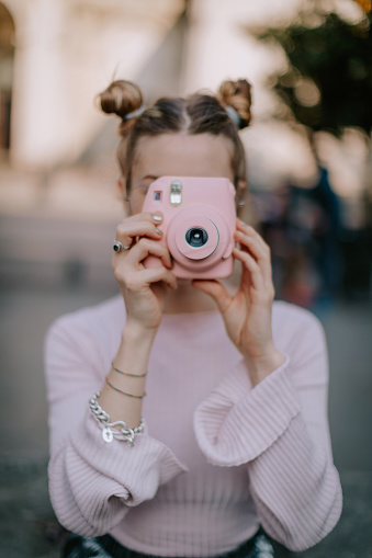 Woman in pink holding pink instant camera