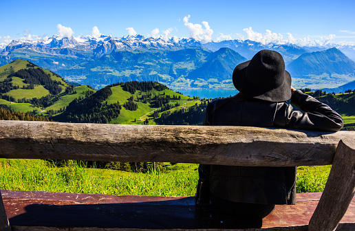 Asian woman on the bench treasures beautiful scenic panoramic view of majestic swiss alps that surrounding Rigi Kulm, the queen of mountains, at Rigi Kulm Station, Lucerne, Switzerland, Europe.