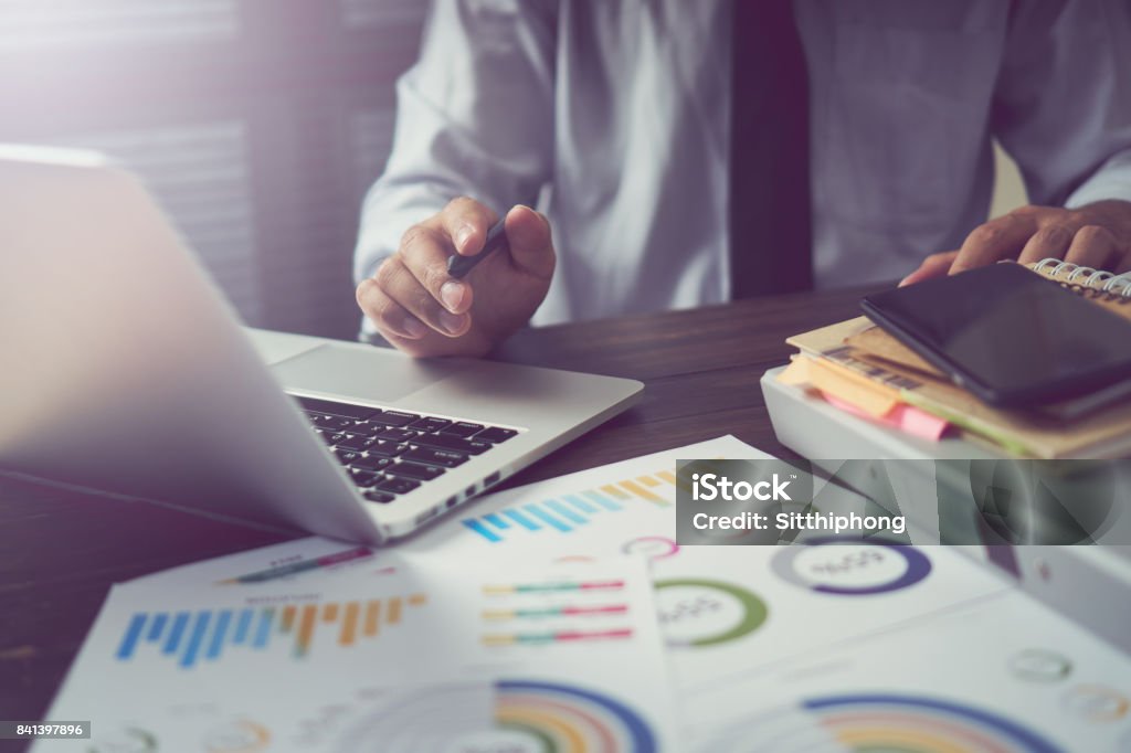 businessman hand working smart phone on wooden desk in office in morning light. The concept of modern work with advanced technology. vintage effect. Accountancy Stock Photo