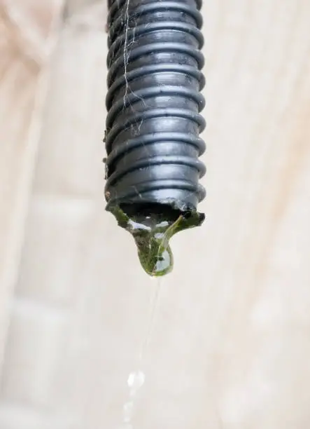 Photo of water running rushing out of black pipe end