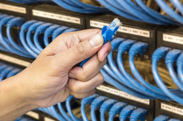 hand holding network cable on the switch hub in server room background