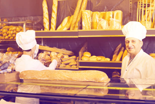 istock staff offering fresh baguettes and buns in bakery 841405790