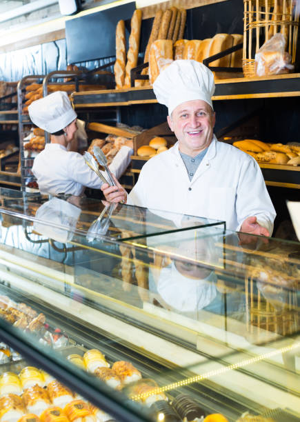 istock senior baker with sweet cakes in local confectionery 841405852