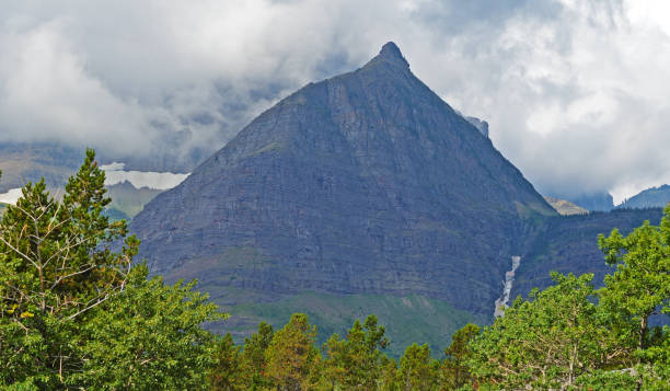 ostry szczyt górski otoczony chmurami w parku narodowym glacier. - lake us glacier national park cloudscape cloud zdjęcia i obrazy z banku zdjęć