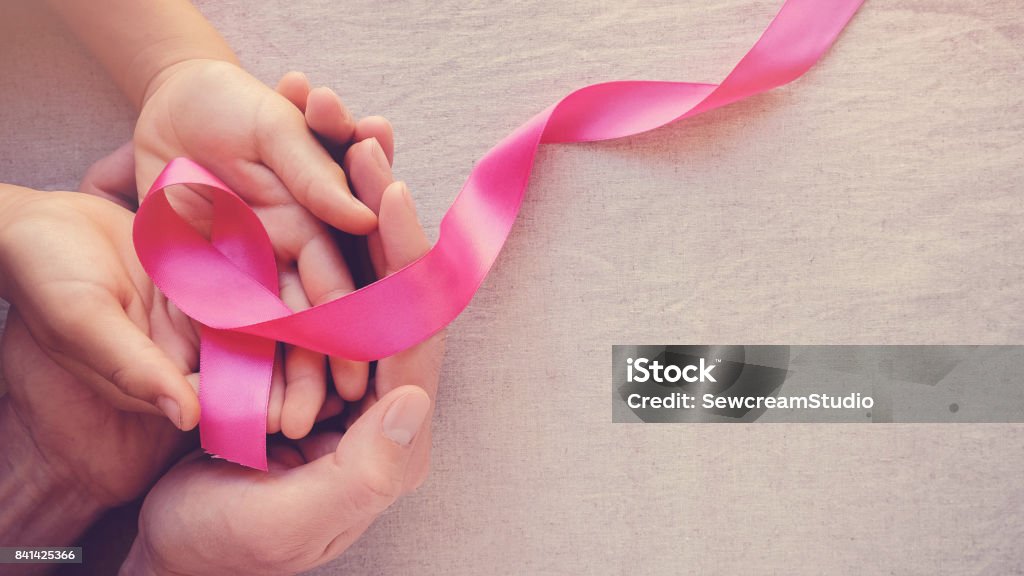 Adult and child hands holding pink ribbons, Breast cancer awareness, abdominal cancer awareness and October Pink panoramic background Breast Cancer Awareness Stock Photo