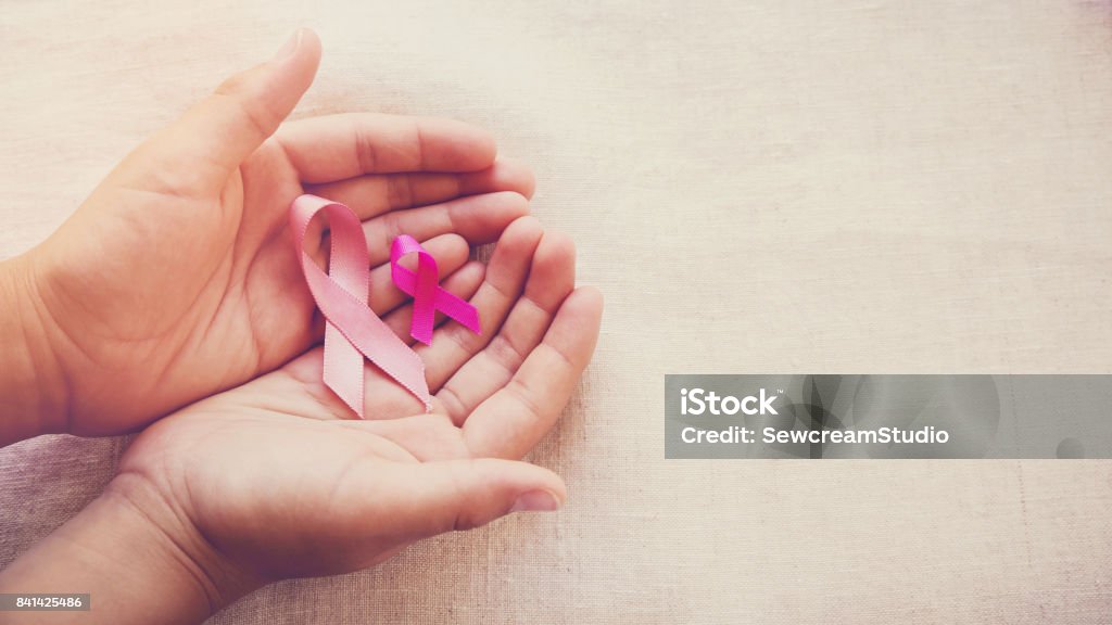 Hands holding Pink Ribbons toning background, Breast cancer awareness and Abdominal cancer awareness Cancer - Illness Stock Photo