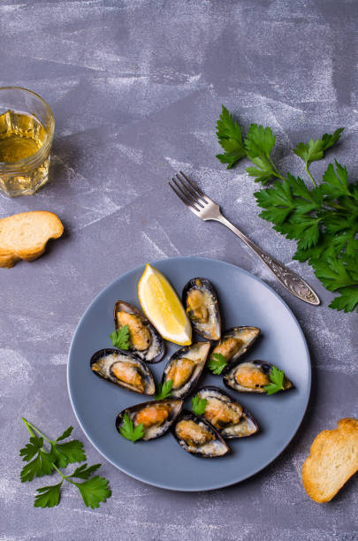 Baked mussels with cheese Baked mussels with cheese, parsley and lemon shells. Selective focus. kosher starter recipes stock pictures, royalty-free photos & images