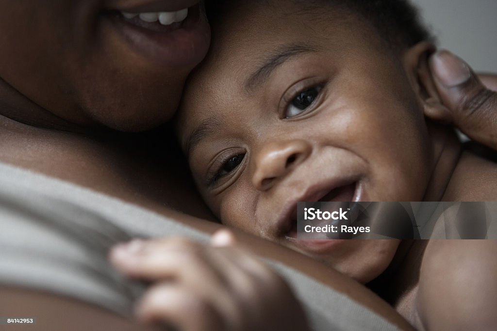 Niño sonriente cuddled por madre - Foto de stock de Bebé libre de derechos