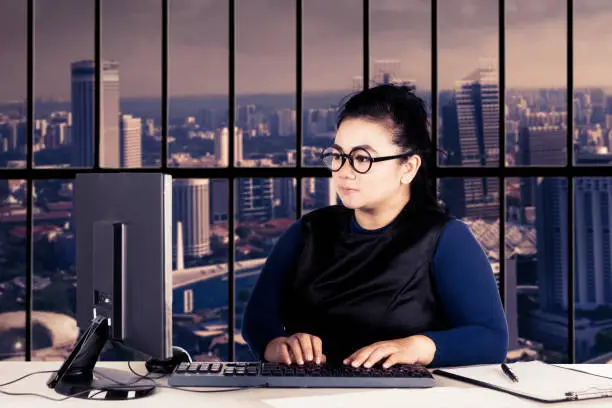 Portrait of pretty businesswoman sitting in front of her computer while typing on the keyboard