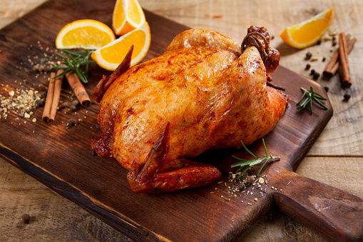 Roasted chicken with spices on wooden background, selective focus. Healthy food, diet or cooking concept