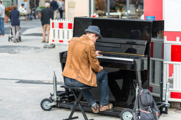Paris, France: A pianist playing an upright piano outside on a sidewalk on Rue de Vaugirard (6th arrondissement).