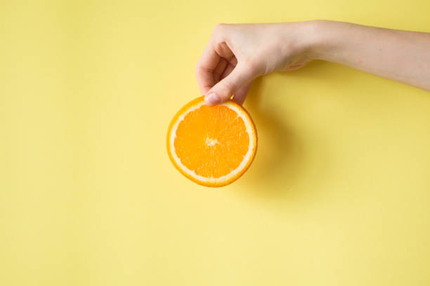istock Hand holding orange on yellow background food concept 841454198