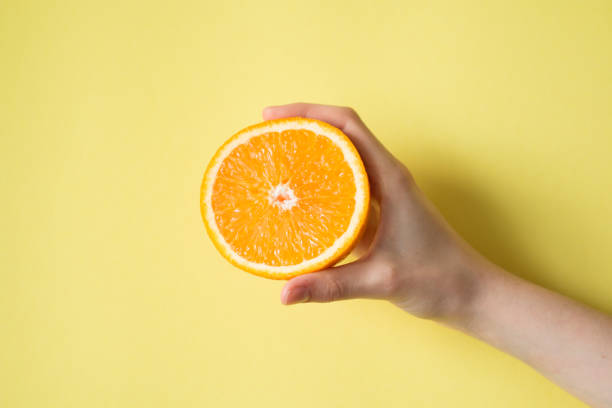 istock Hand holding orange on yellow background food concept 841454228