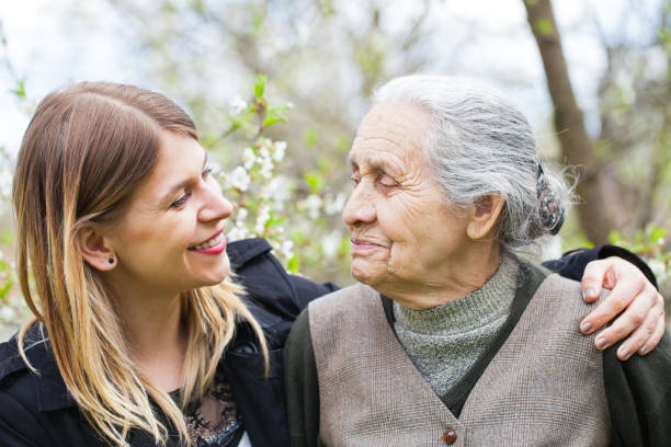 Happy elderly woman with carer outdoor - springtime stock photo