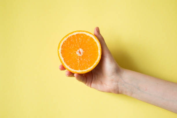 istock Hand holding orange on yellow background food concept 841454342